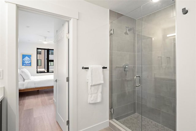 bathroom featuring a shower stall, wood finished floors, baseboards, and connected bathroom