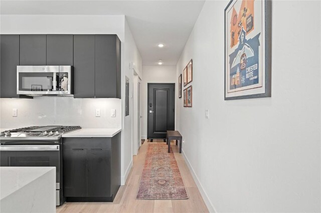 kitchen featuring baseboards, recessed lighting, modern cabinets, light countertops, and appliances with stainless steel finishes