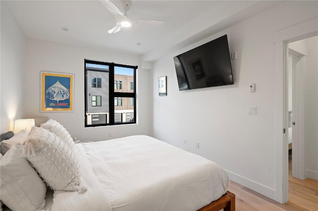 bedroom with a ceiling fan, light wood-style flooring, and baseboards