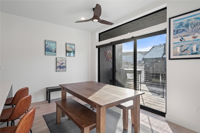 dining space with light wood-type flooring, a ceiling fan, and baseboards