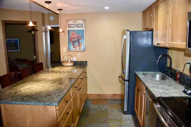 kitchen with hanging light fixtures, stone finish flooring, a sink, dark stone countertops, and baseboards