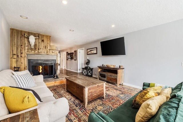 living area featuring recessed lighting, a textured ceiling, baseboards, and a lit fireplace