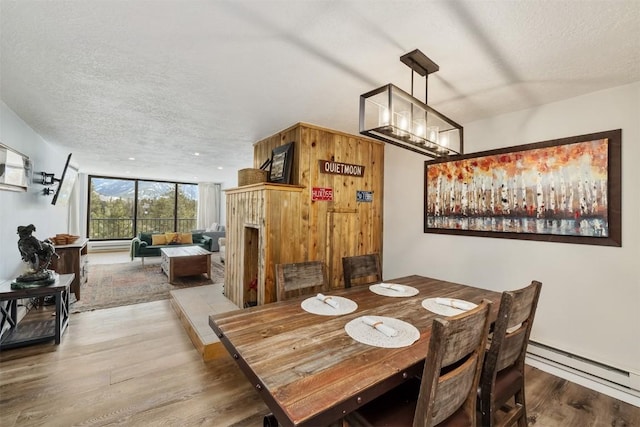 dining area with baseboard heating, wood finished floors, and a textured ceiling