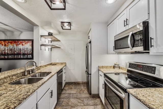 kitchen with baseboards, appliances with stainless steel finishes, a sink, and a textured ceiling