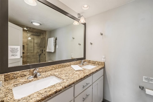 bathroom with double vanity, a shower stall, and a sink