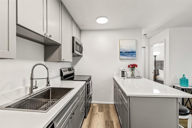 1300 Athens Plz Unit 2, Steamboat Springs, CO 80487 - kitchen with appliances with stainless steel finishes, gray cabinetry, a peninsula, light wood-style floors, and a breakfast bar