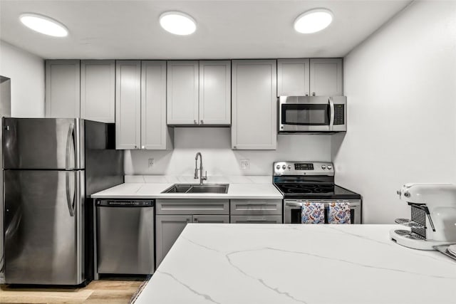 1300 Athens Plz Unit 2, Steamboat Springs, CO 80487 - kitchen with appliances with stainless steel finishes, gray cabinetry, light stone countertops, and light wood-style flooring