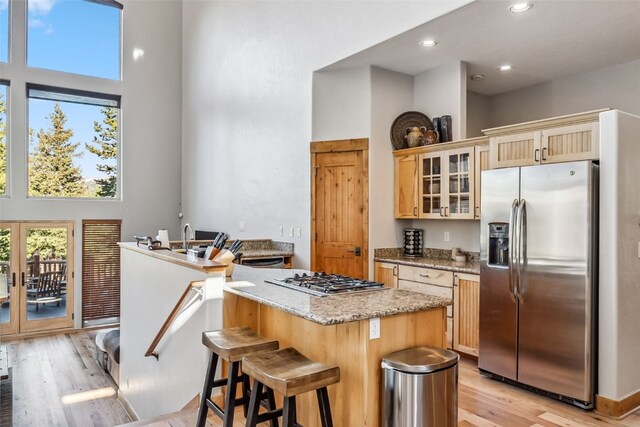 180 Emmett Lode Rd, Breckenridge, CO 80424 - kitchen featuring light wood-type flooring, a towering ceiling, glass insert cabinets, light stone countertops, and appliances with stainless steel finishes