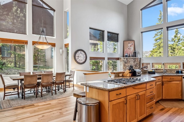 180 Emmett Lode Rd, Breckenridge, CO 80424 - kitchen featuring light wood finished floors, stainless steel gas cooktop, a sink, a high ceiling, and light stone counters