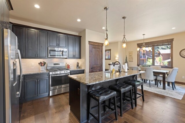 799 Independence Rd Unit 799, Keystone, CO 80435 - kitchen featuring appliances with stainless steel finishes, dark wood-style flooring, light stone counters, decorative backsplash, and an island with sink