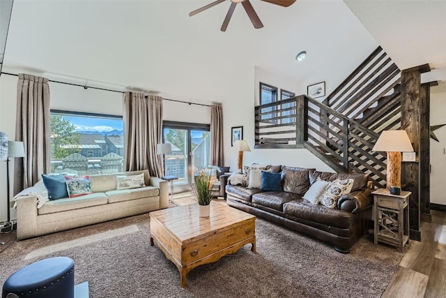 living area with ceiling fan, a healthy amount of sunlight, wood finished floors, and stairs