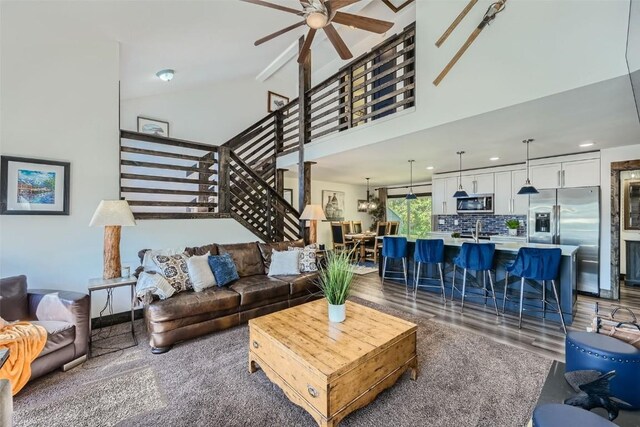 living room with recessed lighting, stairway, wood finished floors, a ceiling fan, and high vaulted ceiling