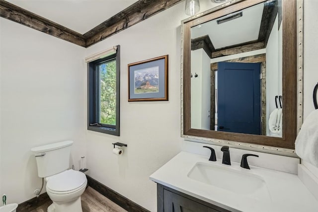 bathroom with wood finished floors, visible vents, toilet, vanity, and baseboards