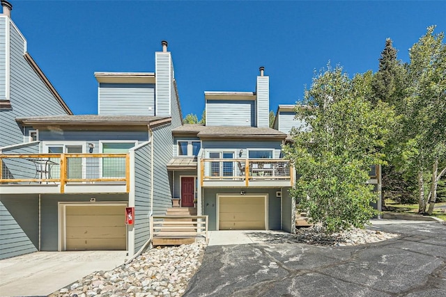 view of front of house with aphalt driveway, a balcony, and a garage