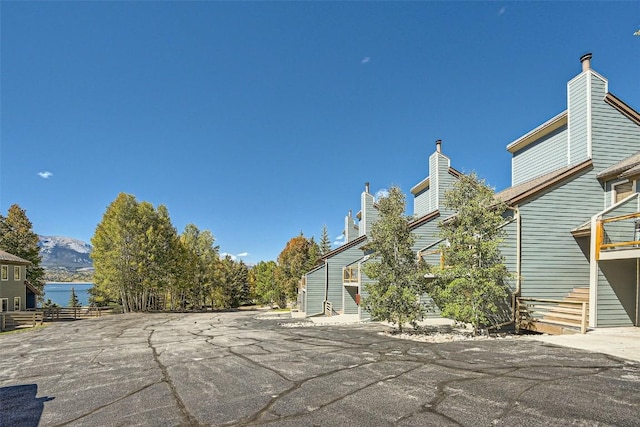 view of property exterior with a chimney, fence, and a mountain view