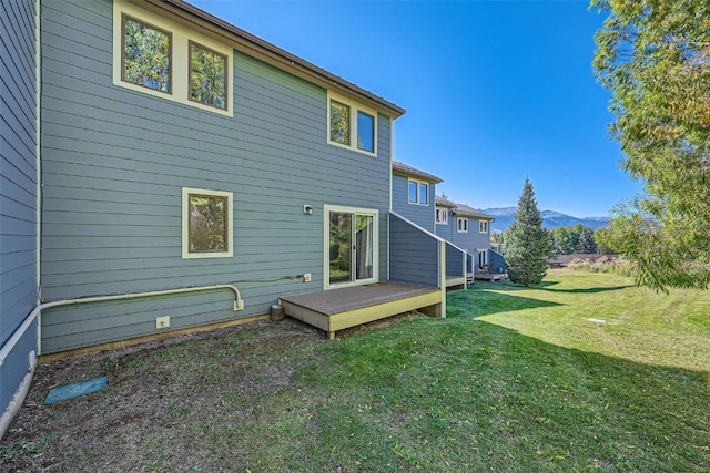 back of property featuring a deck with mountain view and a lawn
