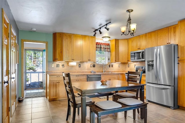216 Ambush Ln, Jefferson, CO 80456 - kitchen featuring appliances with stainless steel finishes, a chandelier, healthy amount of natural light, and light tile patterned flooring