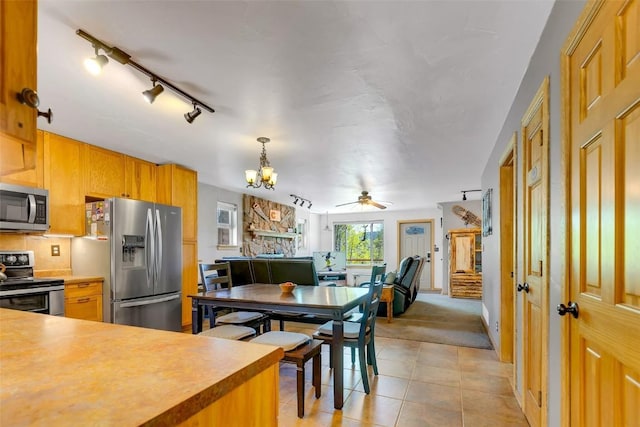 216 Ambush Ln, Jefferson, CO 80456 - kitchen with appliances with stainless steel finishes, a chandelier, open floor plan, ceiling fan, and light tile patterned flooring