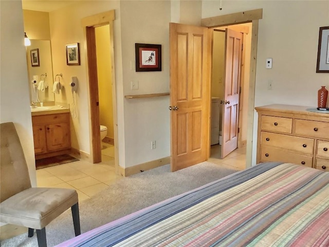 bedroom with ensuite bath, baseboards, a sink, and light tile patterned floors