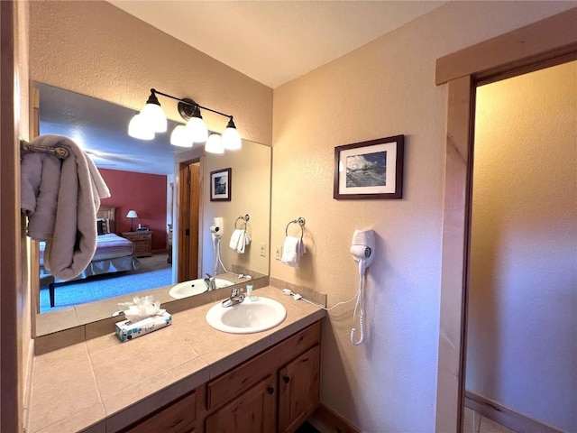 bathroom with a textured wall, vanity, and connected bathroom