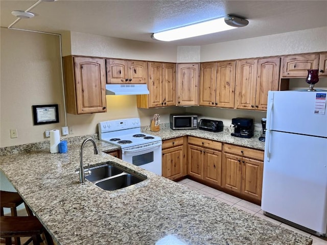 kitchen featuring a sink, a kitchen bar, white appliances, light stone counters, and under cabinet range hood