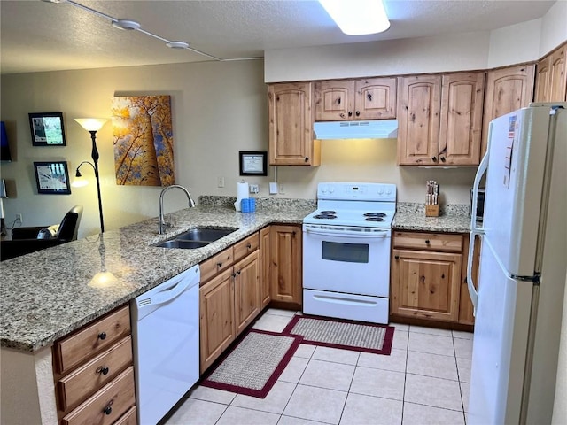 kitchen featuring a peninsula, a sink, white appliances, light stone counters, and under cabinet range hood