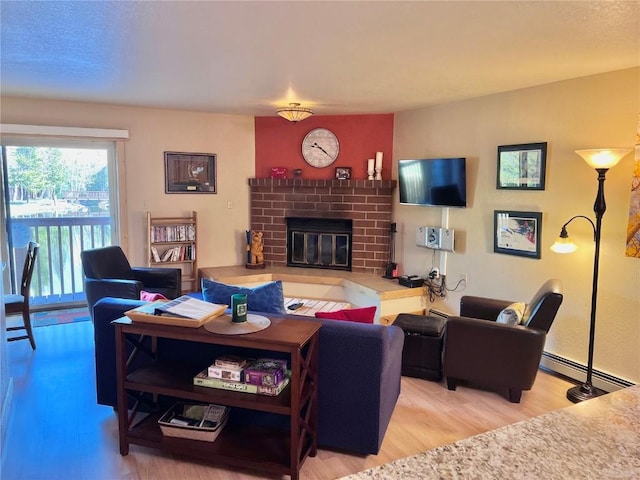 living area with a baseboard heating unit, a brick fireplace, and wood finished floors