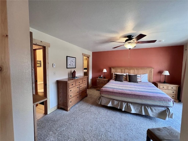 bedroom with light carpet, ensuite bath, a textured ceiling, and ceiling fan