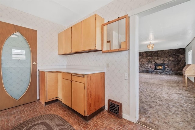 401 Moffat Ave, Oak Creek, CO 80467 - kitchen featuring wallpapered walls, brick patterned flooring, a wood stove, light countertops, and baseboards