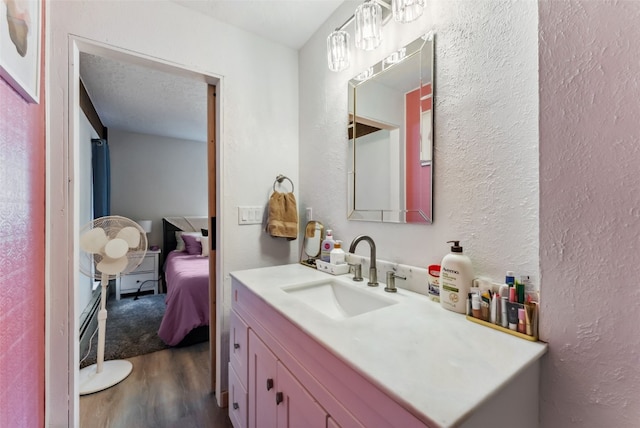 ensuite bathroom featuring a textured wall, vanity, wood finished floors, and ensuite bathroom