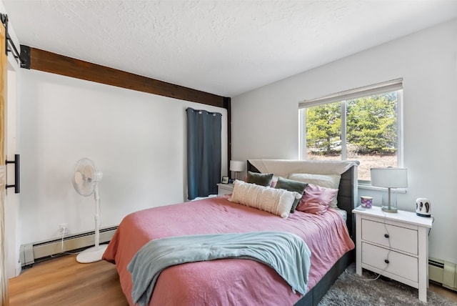 bedroom with baseboard heating, wood finished floors, and a textured ceiling