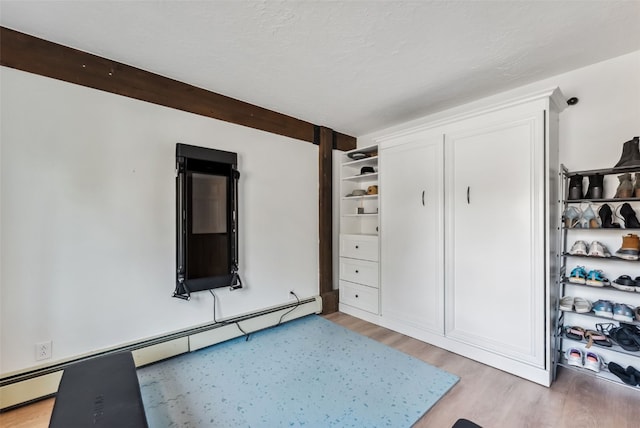 unfurnished bedroom with light wood-type flooring and baseboard heating