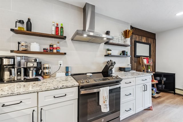 kitchen featuring light stone counters, open shelves, electric stove, wall chimney range hood, and light wood-type flooring