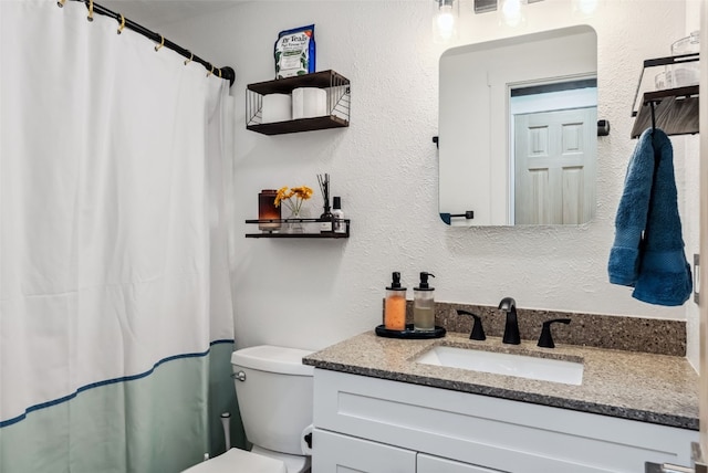 bathroom with a textured wall, vanity, a shower with shower curtain, and toilet
