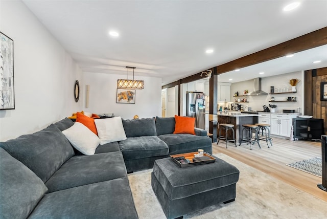 living area featuring light wood finished floors, recessed lighting, and wet bar