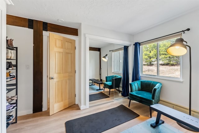 sitting room featuring light wood finished floors, baseboards, and a textured ceiling