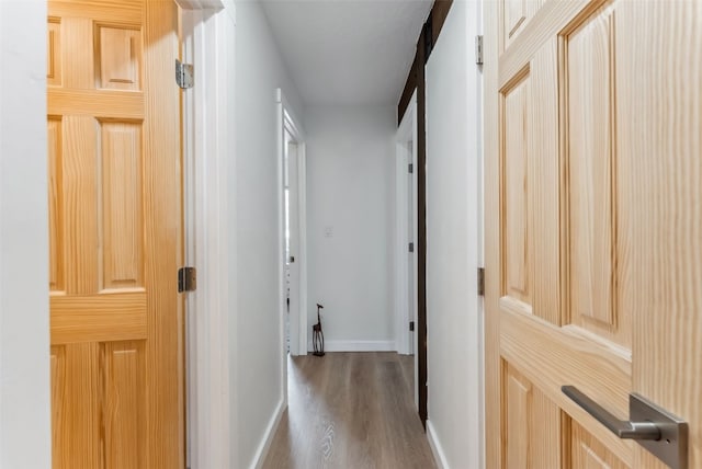 corridor with baseboards and wood finished floors