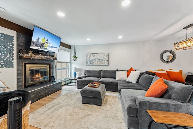 living room with a glass covered fireplace, wood finished floors, and recessed lighting