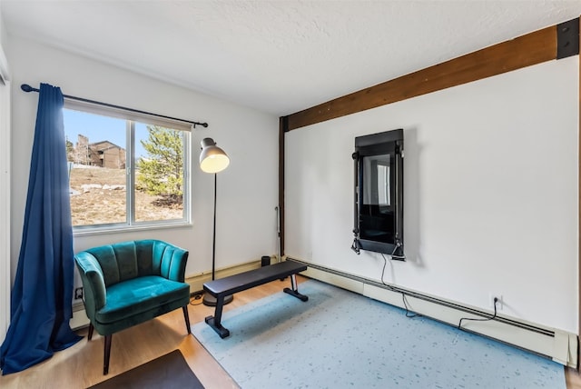 living area featuring a baseboard radiator, wood finished floors, and a textured ceiling