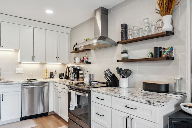 kitchen with stainless steel appliances, white cabinetry, decorative backsplash, wall chimney range hood, and open shelves