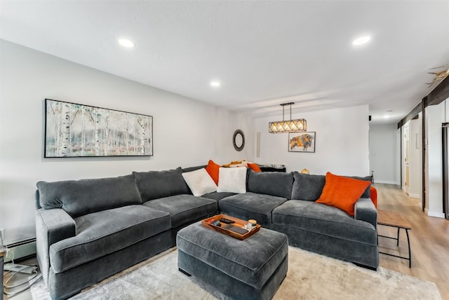 living room featuring a baseboard radiator, light wood-style flooring, and recessed lighting