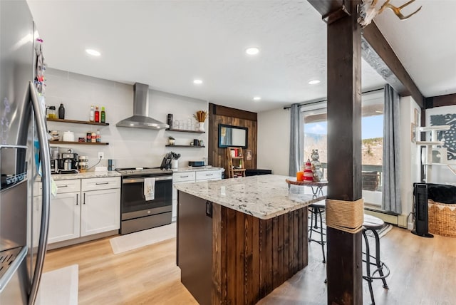 kitchen featuring open shelves, wall chimney range hood, light wood finished floors, and stainless steel appliances