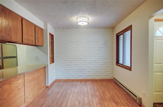 8 Sequoia Ct Unit 8, Steamboat Springs, CO 80487 - unfurnished dining area featuring a baseboard radiator, light wood-type flooring, a textured ceiling, and baseboards