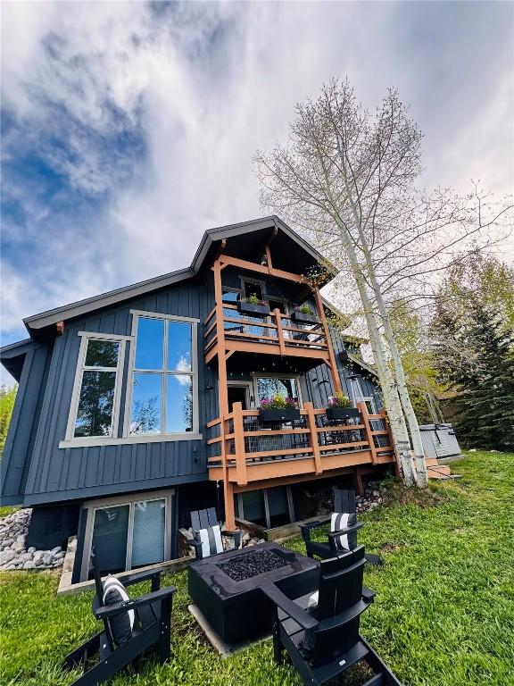 402 Kestrel Ln, Silverthorne, CO 80498 - back of house featuring an outdoor fire pit, board and batten siding, a wooden deck, a lawn, and a balcony