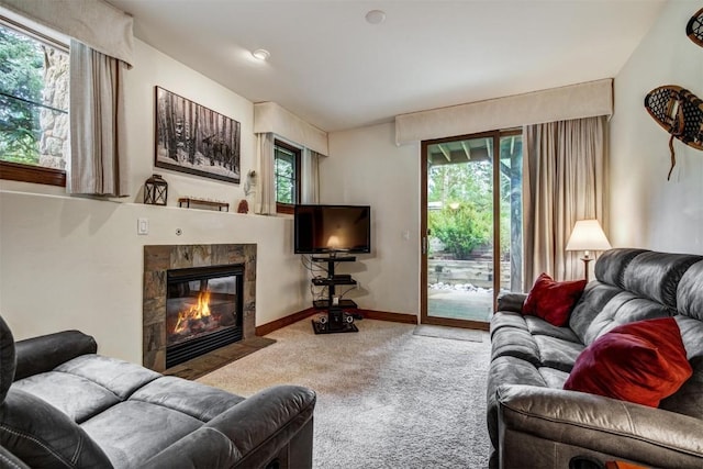 carpeted living area with a tile fireplace and baseboards