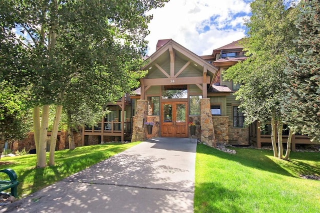 view of front of house featuring stone siding, a front yard, and french doors