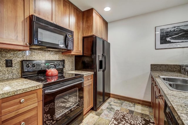 kitchen featuring black appliances, baseboards, a sink, tasteful backsplash, and tile counters