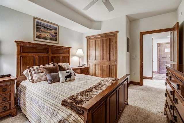 bedroom featuring light colored carpet, a closet, baseboards, and ceiling fan