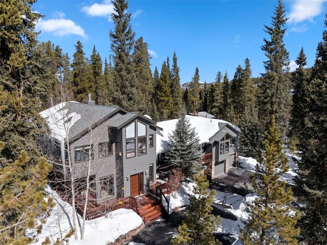 284 Lakeshore Loop, Blue River, CO 80424 - view of snowy exterior with an attached garage, driveway, a wooded view, and a chimney