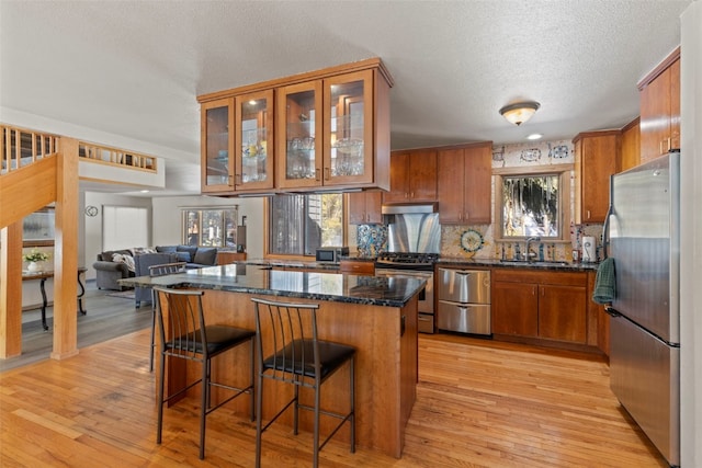 284 Lakeshore Loop, Blue River, CO 80424 - kitchen featuring stainless steel appliances, brown cabinetry, a textured ceiling, under cabinet range hood, and a kitchen island